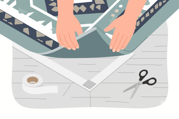 Obraz premium Female hands folding quilted textile with scissors and tape on table.