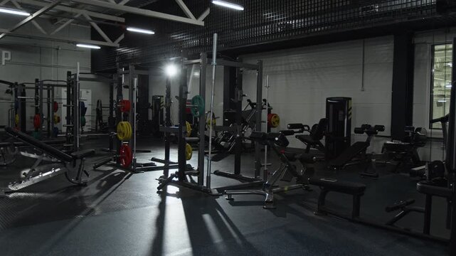 Empty modern gym interior showing professional fitness equipment standing under bright spotlights. Footage for promoting fitness club memberships or workout gear brands