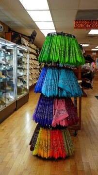 Colorful bandanas displayed inside Chicago western clothing store. Green, blue, purple, pink and yellow textiles hang on a rotating rack beside cowboy hats.