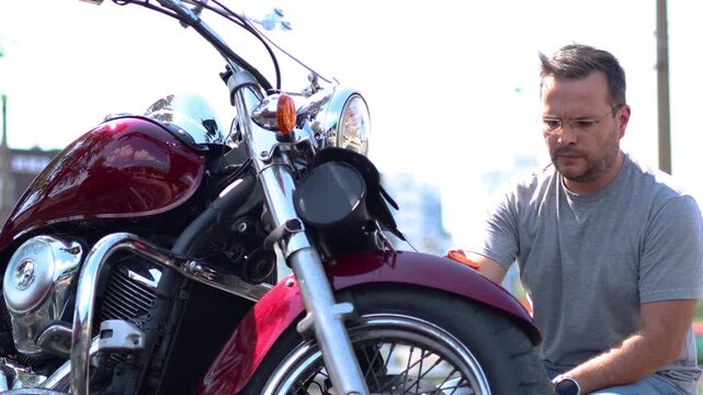 A motorcyclist carefully wipes the front fender of his motorcycle. He wipes the bike with a rag after applying polish. Slow motion 4k footage.