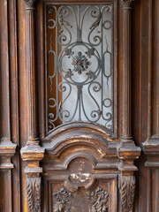Fototapeta premium Ornate Antique Wooden Door with Decorative Wrought Iron and Carved Details, Historic Architectural Entrance, Elegant Traditional Craftsmanship and Vintage European Design