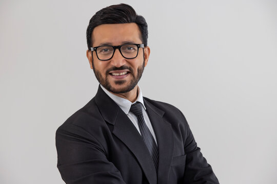 Portrait of a corporate employee in formal business suit smiling against plain backdrop.