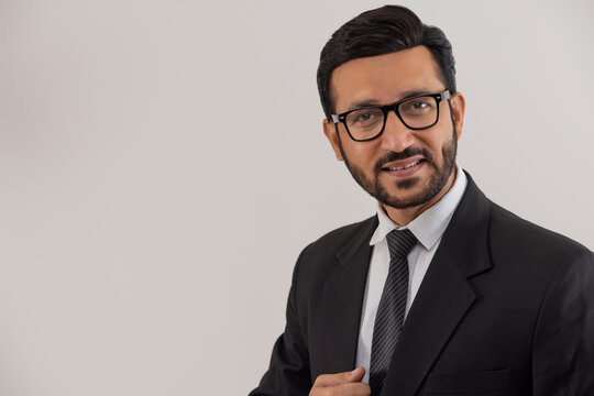 Portrait of a corporate employee in formal business suit smiling against plain backdrop.