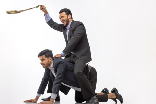 A boss riding on subordinate's back while swirling his necktie in air.