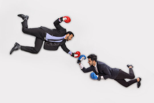 Corporate employees in formal business wearing boxing gloves floating against white background.