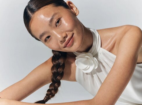 A beautiful young Asian woman with a braided hairstyle smiling in a studio