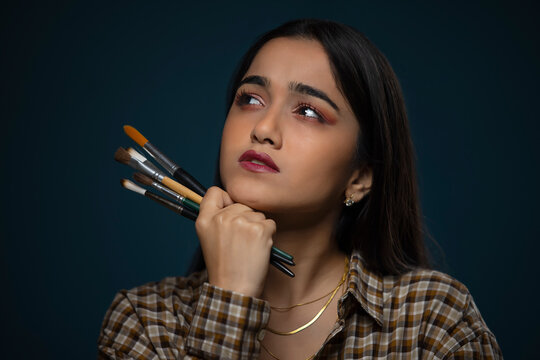 Young artist girl holding brushes and thinking for a new idea
