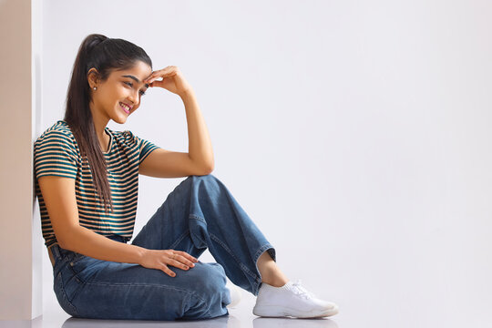 Young woman sitting with her hand on her forehead and looking away with smile