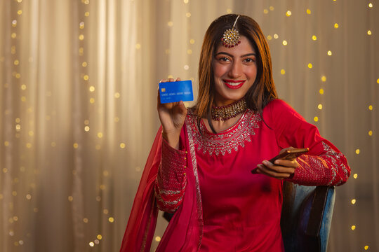 Indian girl in traditional outfit showing her debit card during online shopping