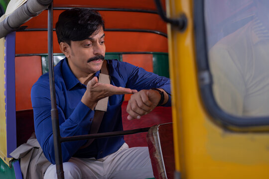 Man in Auto Rickshaw watching wrist watch for getting late for office