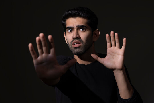 Portrait of a scared young man gesturing with his hands