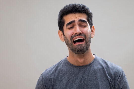 Portrait of a sad young man crying with eyes closed