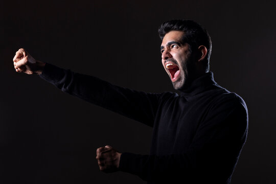 Portrait of a handsome young man cheering with raising fists