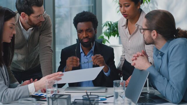 Diversity business team executives showing paper data to African American boss explaining growth profit success at office meeting. Five multiethnic businesspeople excited talking discussing chart