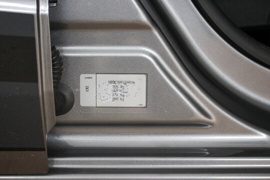 Close up of a VIN and weight label in a new car door gap