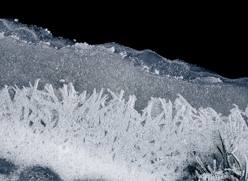 Ice crystals white textured background. Frozen texture. Textured cold frosty surface of the ice on a black background.