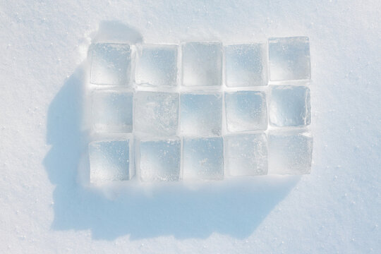 Natural ice cubes stack in a rectangular shape on a snow background. Natural pattern. Refreshing concept.