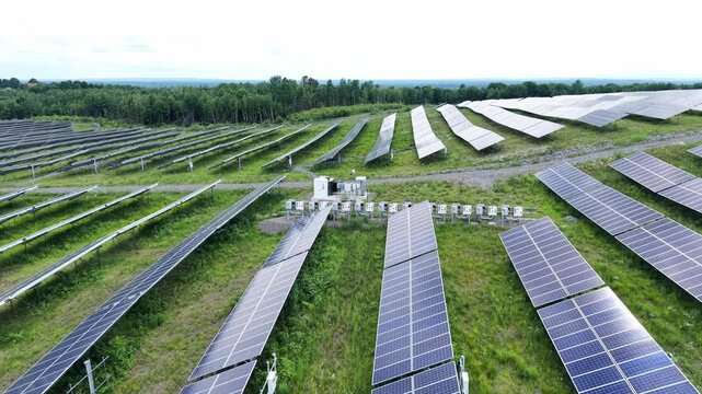 Aerial perspective of a large solar farm with long rows of photovoltaic panels across a grassy field, highlighting renewable energy, sustainable technology, clean power generation