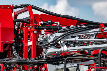 Agricultural field sprayer folded boom mechanism for pesticide application. Modern crop protection machinery frame assembly with hydraulic hoses and farming transport equipment technical detail. © NastyaPhoto