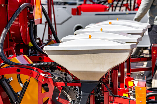 Agricultural seeder row unit plastic seed hoppers for sowing machinery. Modern farming planter component closeup view with chemical tanks and industrial technical details for tractor vehicle.