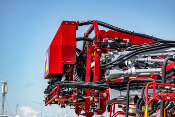 Agricultural field sprayer folded boom mechanism for pesticide application. Modern crop protection machinery frame assembly with hydraulic hoses and farming transport equipment technical detail. © NastyaPhoto