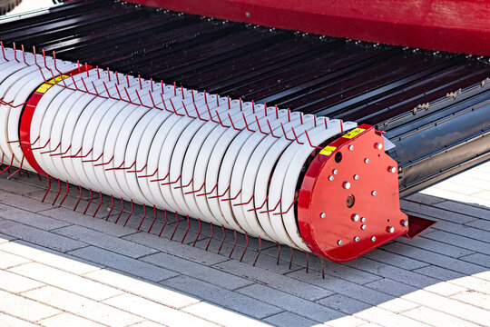 Agricultural round baler pick up reel mechanism for haymaking. Modern farming forage harvester equipment component closeup view with spring tines and industrial machine mechanical details.