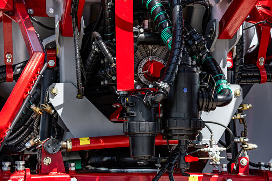 Agricultural field sprayer liquid filter manifold and pump assembly. Modern crop protection machinery fluid system component with high pressure hoses and farming vehicle technical details.