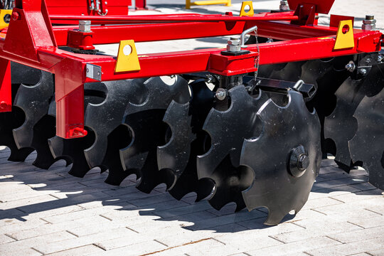 Agricultural disc harrow notched blades for soil cultivation. Modern farm machine tillage equipment unit component closeup view with steel axle and industrial technical details for tractor.