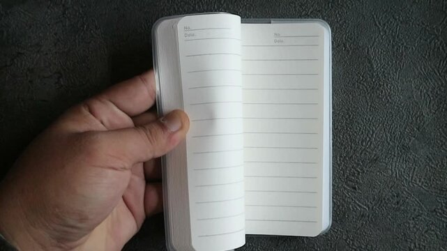 Someone is flipping through the pages of a blank book very quickly, using only one hand.