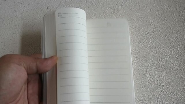 Someone is flipping through the pages of a blank book very quickly, using only one hand.