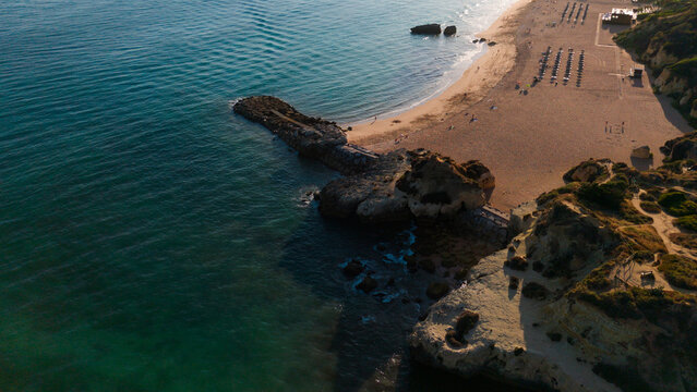 peaceful rocky outcrop on sandy beach with blue water and green foliage, aerial view of serene coastal landscape for vacation destination and beachside retreat. Praia dos Aveiros Portugal