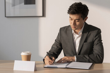 Fototapeta premium Businessman Writing Notes in Modern Office with Coffee