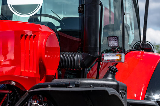 Agricultural tractor cabin front pillar with led position lights. Modern farm machinery engine hood closeup view with glass windshield and industrial transport vehicle technical details.