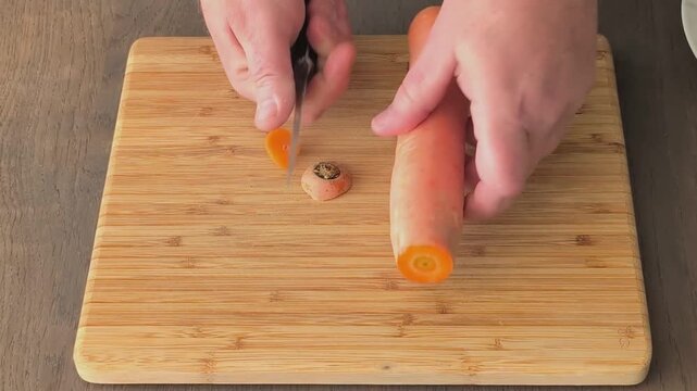 Cutting off the head and tail of carrots before peeling them in a kitchen setting