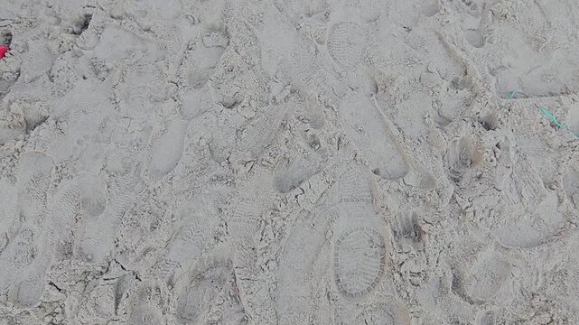 texture of stone,Footprints mark the sand's quiet expanse. Each step leaves a faint, soft imprint. The beach holds echoes of footsteps. Sunlight glints across the pale grains. Calm, solitary beach sce