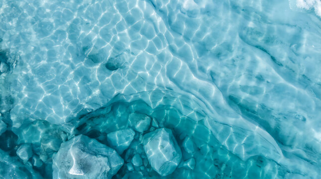 Clear turquoise water with sunlight reflections reveals smooth underwater rocks, creating a serene and refreshing aquatic scene.