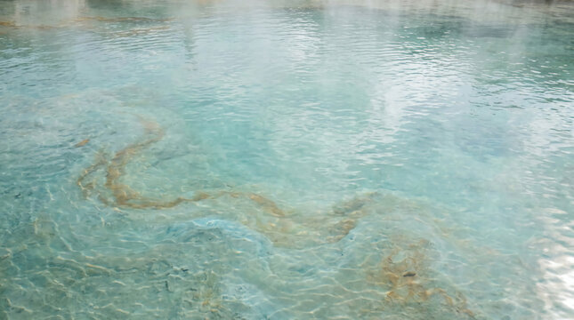 Clear turquoise water with visible natural sediment patterns and gentle ripples on the surface.