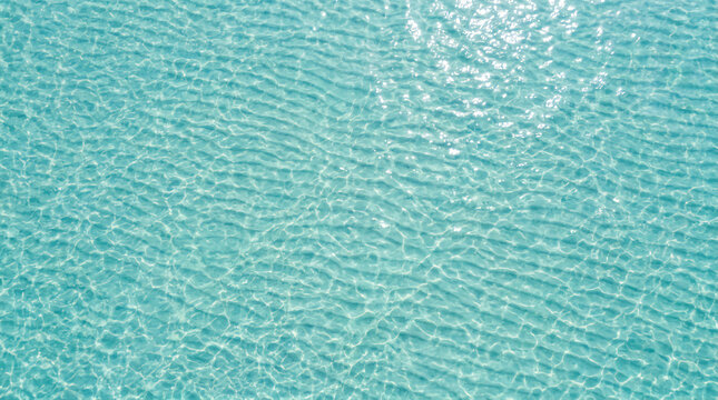 Clear turquoise water with sunlight reflecting on gentle ripples, creating a sparkling pattern on the surface.