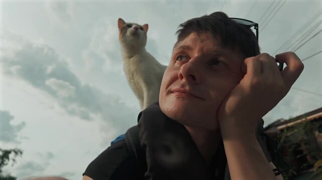 Man with white cat sitting on shoulder during boat ride, Peaceful moment with cute kitty on male traveler backpack 4k