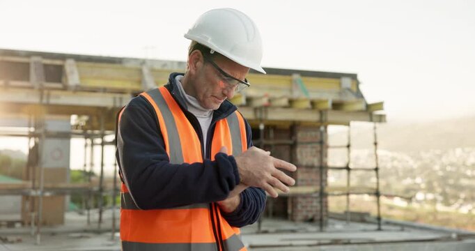 Engineer, man and wrist pain on construction site with injury, building accident and massage for relief. PPE, mature person and hurt hand outdoor with civil engineering error, sprain and overworked.