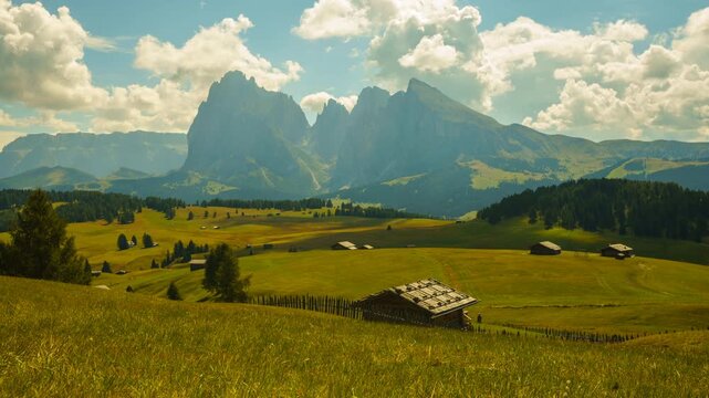 Timelapse of the Dolomites in Italy featuring alpine meadows and dramatic mountain peaks on a sunny day