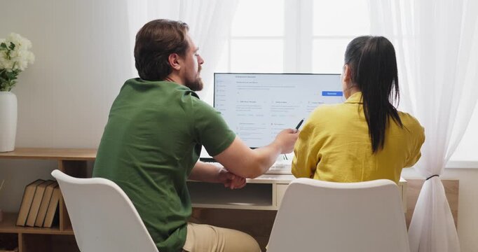 Couple budget planning on computer at home. They review a finance dashboard to track expenses and set savings goals using tools in home office. Budgeting and money management concept