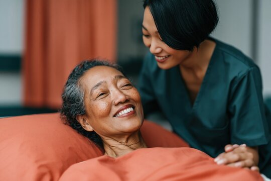 Tender bedside moment of elderly patient and smiling nurse for senior care background and compassionate hospital poster