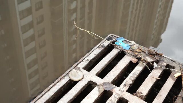Rainwater collected near a storm drain grate on a residential building representing drainage systems, urban infrastructure and maintenance