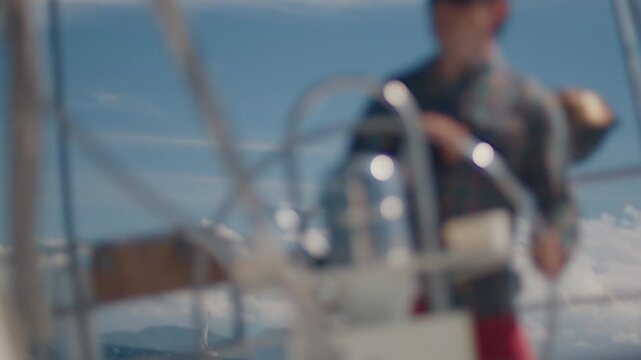 Young man sailor sailing alone the small sailing boat in the fresh sea during nice sunny day. Sailor enjoys the wind. Confident sailor steers the sail boat