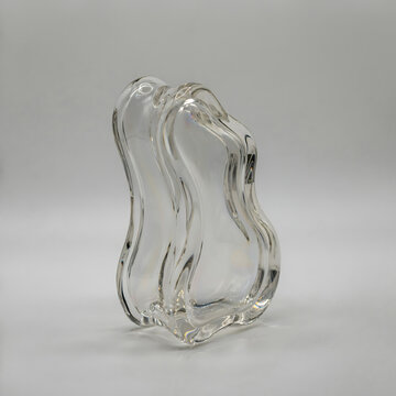 Elegant abstract clear glass vase with vertical fluid wavy curves on white studio background