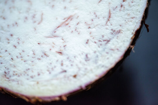 Close-up of a sliced taro root showing its white and purple speckled interior.