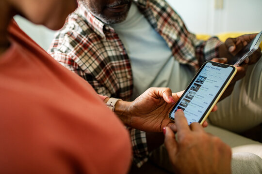Senior couple booking vacation rental on smartphone at home