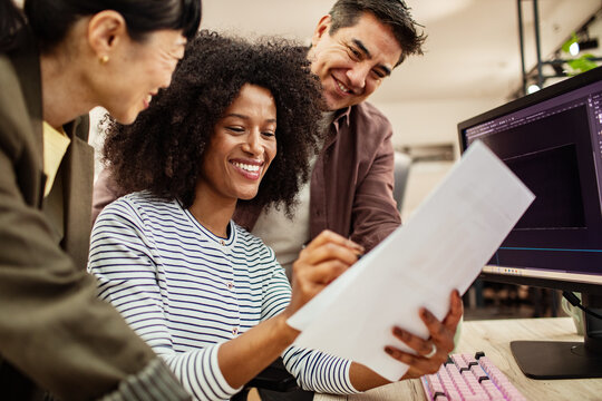 Creative team reviewing design documents at office desk