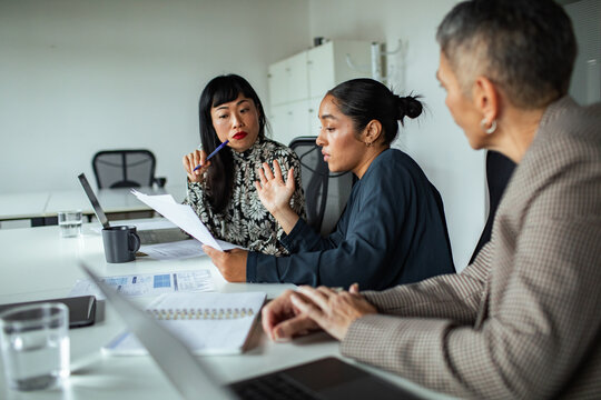 Three businesswomen discussing a report in a conference room